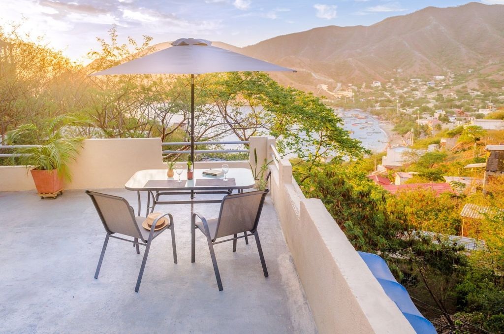 Terraza de un alojamiento turístico con vistas a la bahía al atardecer, mesa preparada para cenar