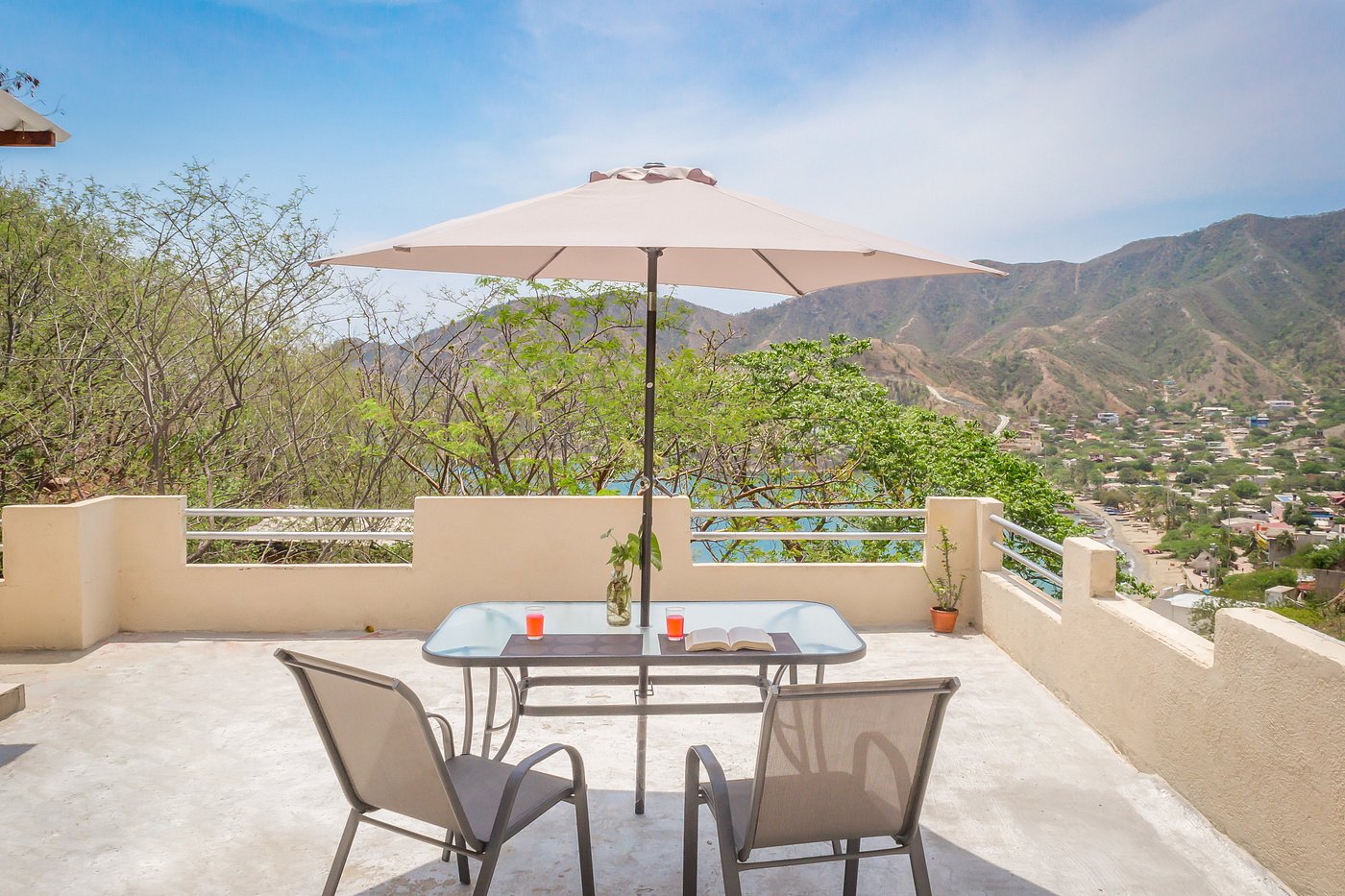 Terraza con sombrilla y vistas a la bahía y las montañas en un alojamiento turístico
